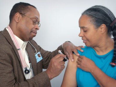 Black doctor vaccinating Black woman