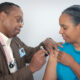 Black doctor vaccinating Black woman